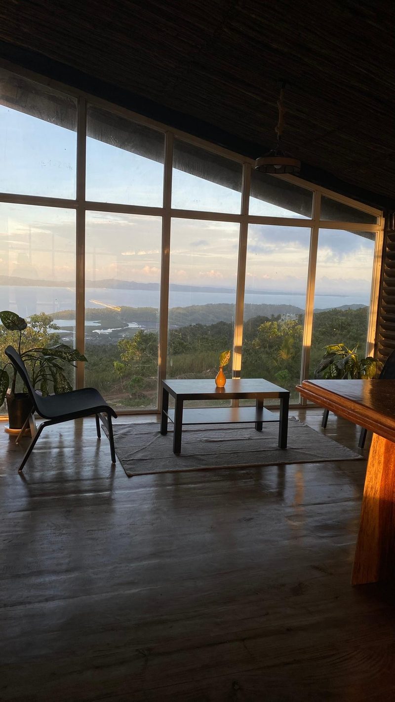 Floor-to-ceiling windows framing the bay at sunrise from inside the resort